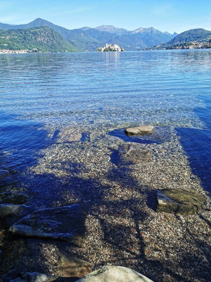 L'acqua limpida del lago con sullo sfondo l'Isola e le montagne — Lago d'Orta, fotografia di Patrizia Franzina